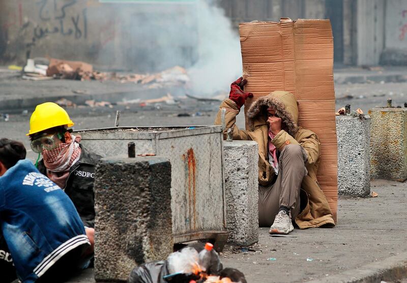 Anti-government protesters take cover during clashes with security forces in central Baghdad. AP Photo