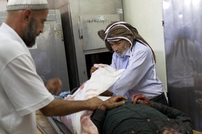 Sheik Ahmed Tarrouch, right, known as Abu Mohammed, prepares the body of Achmed Benasawi, 22, in the morgue at the Kamal Adwan Hospital in Beit Lahiya on July 18, 2014. Photo by Heidi Levine for The National