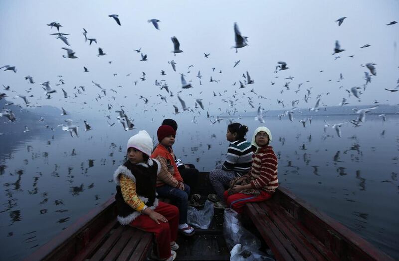 Migratory birds fly above children taking a boat ride in the waters of river Yamuna in old Delhi. Ahmad Masood / Reuters