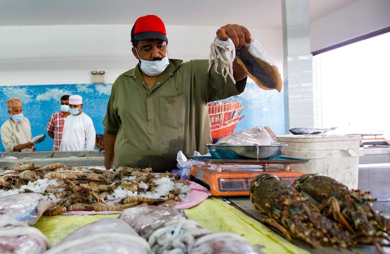 A vendor wearing a face mask against the coronavirus sells fresh fish at the Mutrah Souq in the Omani capital Muscat.   AFP