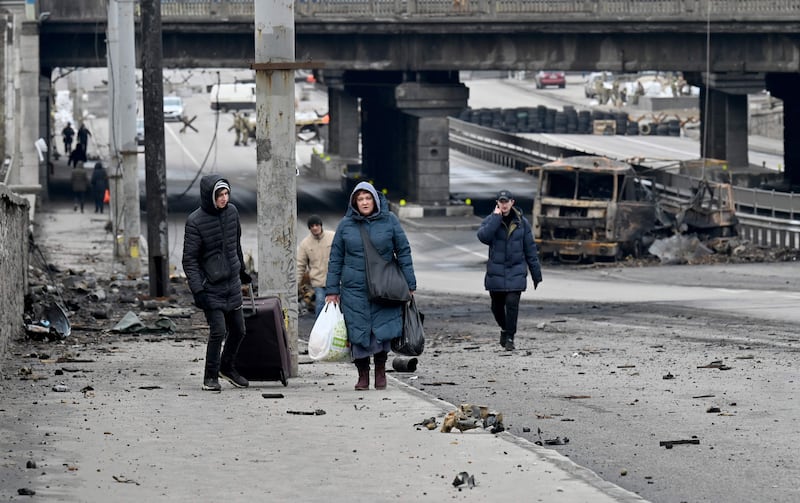 People carry their belongings past the debris of last week's combat in Kyiv. AFP