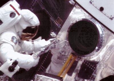 Astronaut Jeff Hoffman uses a power wrench to loosen bolts on an access door on the Hubble Space Telescope 05 December 1993 during the first of five planned spacewalks scheduled to repair the spacecraft. Hoffman and crewmate Steve Musgrave successfully installed new gyroscopes and electronics in the telescope. / AFP PHOTO