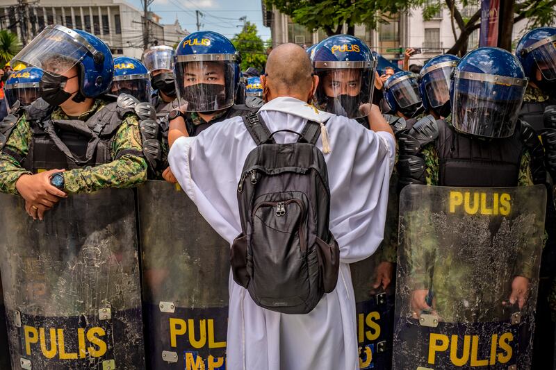 A Catholic priest talks to police officers standing guard as Filipinos take part in a protest against election results in Manila.  Getty Images