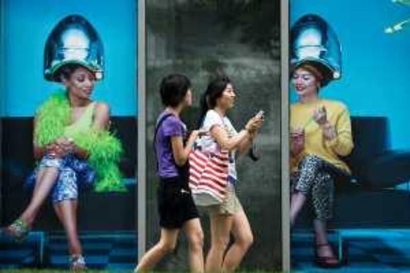 Chinese women walk past a commercial shop lot displaying a poster of women doing hairstyle in Beijing, China, Monday, July 13, 2009. Economists have pointed to increased activity in residential and commercial real estate as signs China is emerging from its slump as Beijing's 4 trillion yuan (US$586 billion) stimulus plan pumps money into the economy. (AP Photo/Andy Wong) *** Local Caption ***  XAW103_China_Economy.jpg