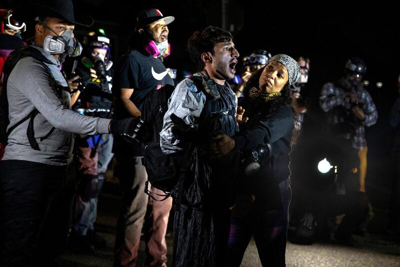 A protester screams at police as they attempt to take control of the streets with Portland protests reaching 100 consecutive nights on Saturday, Sept. 5, 2020, in Portland, Ore. Hundreds of people gathered for rallies and marches against police violence and racial injustice Saturday night in Portland, Oregon, as often violent nightly demonstrations that have happened for 100 days since George Floyd was killed showed no signs of ceasing.(AP Photo/Paula Bronstein)