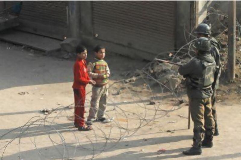 Kashmiri children ask Indian paramilitary soldiers permission to cross barbed wire set up as a road block on the fourth consecutive day of a curfew imposed after the execution of a Kashmiri man.