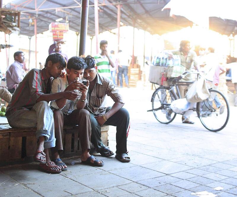 Porters relax and check their mobile phones while waiting for customers. Subhash Sharma for The National