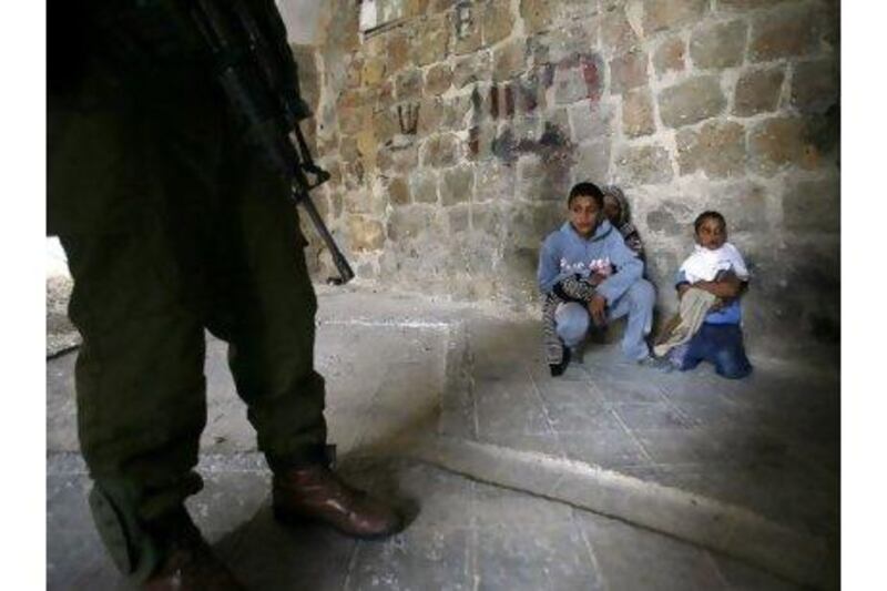 An Israeli soldier stands guard next to three Palestinian boys who were arrested for throwing stones during clashes in the West Bank city of Hebron. Hazem Bader / AFP Photo