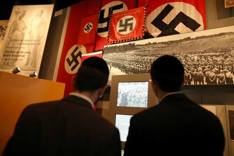 FILE PHOTO: Nazi German flags bearing swastikas are seen as visitors look at part of an exhibition in the Holocaust History Museum at the Yad Vashem World Holocaust Remembrance Center in Jerusalem January 15, 2020. REUTERS/Ammar Awad/File Photo