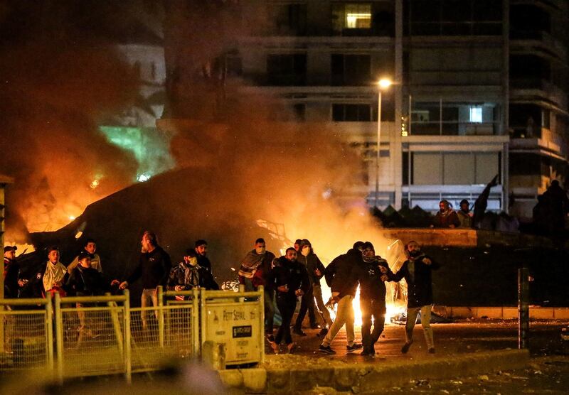 Protesters throw stones at riot police, next burning tents during clashes in central Beirut. EPA