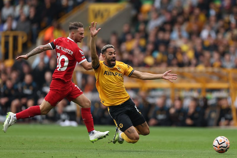 Liverpool's Alexis Mac Allister is given a yellow card for pulling back Matheus Cunha of Wolves. AFP