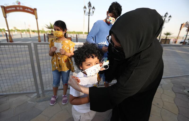 A mother helps her child put on his face mask at Global Village in Dubai as it reopens on October 25, 2020. EPA