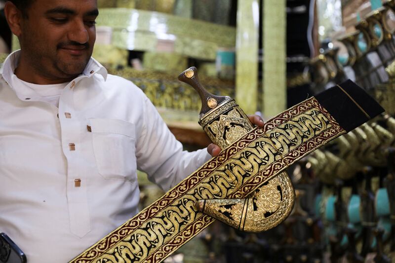 A vendor displays a Yemeni traditional dagger, or jambiya, with its belt made of metallic golden threads, at his shop in the old quarter of Sanaa, Yemen May 15, 2023.  REUTERS / Khaled Abdullah