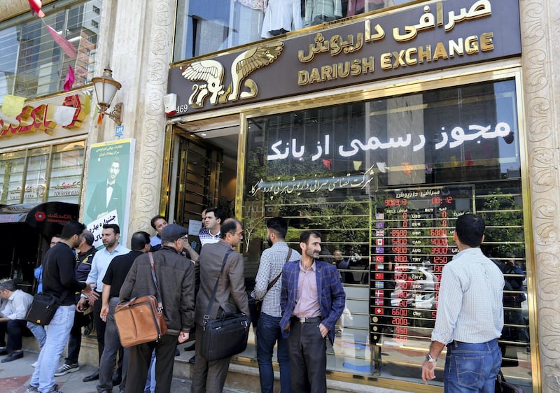 Iranians walk past a currency exchange shop in the capital Tehran on April 10, 2018.
Iran took the drastic step of fixing the rate of its currency against the dollar in a bid to arrest a slide that has seen it fall by a third in six months. / AFP PHOTO / ATTA KENARE