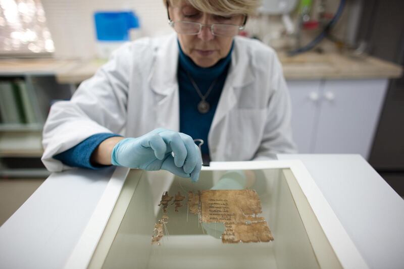 JERUSALEM, ISRAEL - DECEMBER 18:  (ISRAEL OUT) A conservation analyst from the Israeli Antiquities department prepares fragments of the 2000-year-old Dead Sea scrolls at a laboratory before photographing them on December 18, 2012 in Jerusalem, Israel.  More than sixty years after their discovery Israel have put 5,000 fragments of the ancient Dead Sea scrolls online in a partnership with Google. (Photo by Uriel Sinai/Getty Images)