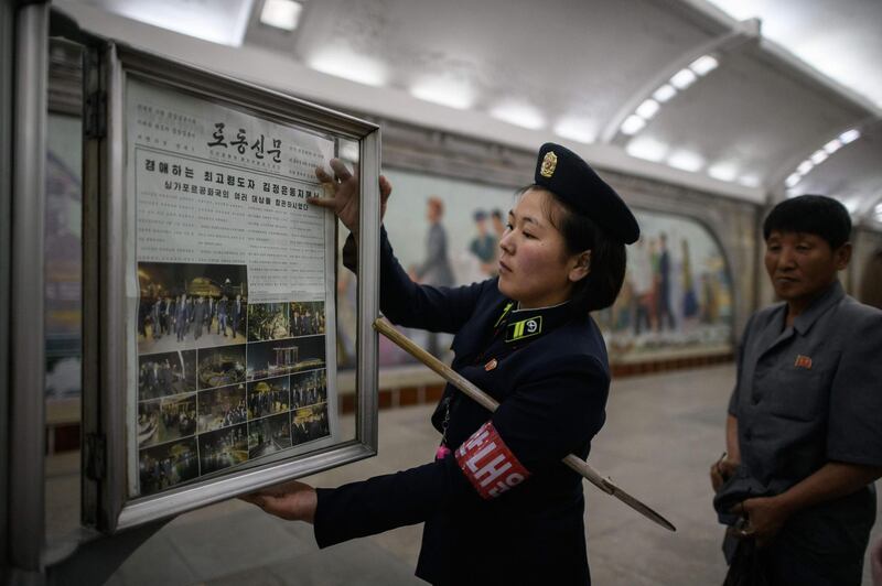 A conductor changes the newspaper to the latest edition showing images of North Korean leader Kim Jong Un in Singapore, at a news stand on a subway platform of the Pyongyang metro, in North Korea. Ed Jones / AFP