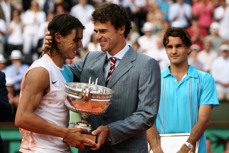 PARIS - JUNE 10:  Rafael Nadal (L) of Spain smiles as he holds the Philippe Chatrier Trophy after winning against Roger Federer (R) of Switzerland with former winner Gustavo Kuerten (C) after the Men's Singles Final on day fifteen of the French Open at Roland Garros on June 10, 2007 in Paris, France.  (Photo by Clive Brunskill/Getty Images)