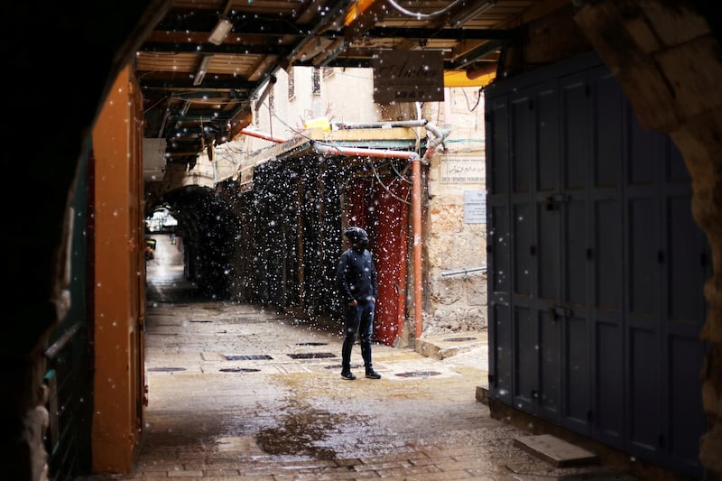 A man looks on as snows falls in an alley of Jerusalem's Old City, February 17, 2021. Reuters