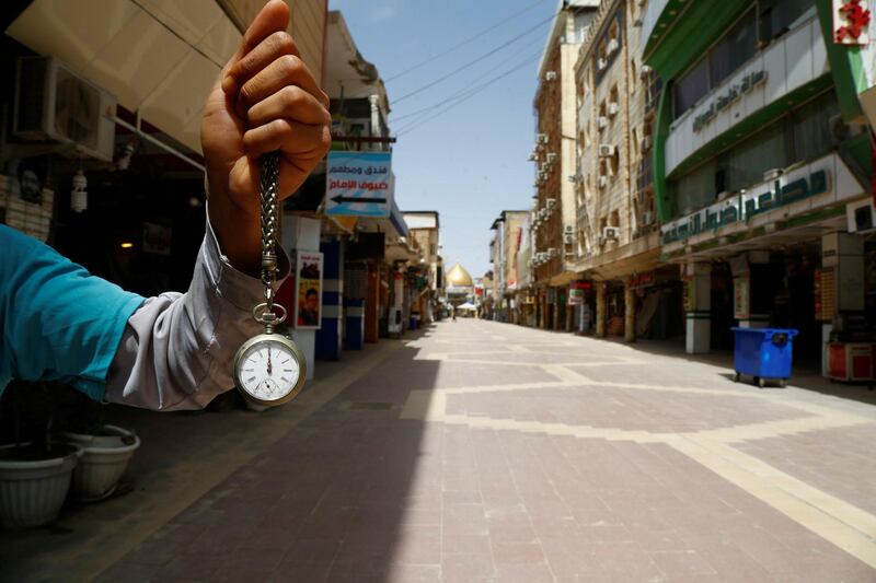A man holds a pocket watch at noon, as he shows the time while posing for photo at an almost empty market near the Imam Ali shrine, during the coronavirus disease outbreak, in Najaf, Iraq. Reuters