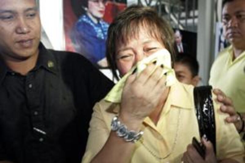 Baby Dante, a supporter of the late Philippine president Corazon Aquino, is escorted as she grieves at the De La Salle school gym.