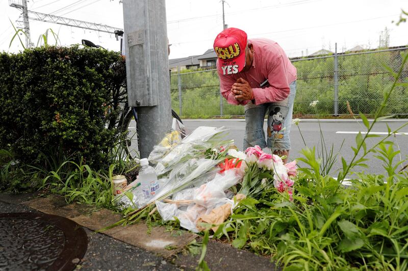 A man prays after placing flowers near the torched building. Reuters