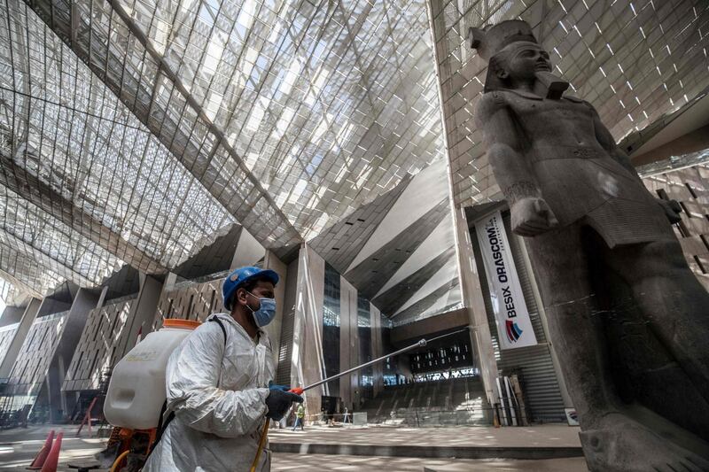 An Egyptian municipality worker disinfects the area around the 3,200-year-old pink-granite colossal statue of King Ramses II at the entrance of the the Grand Egyptian Museum, which is currently under construction, in Giza, Cairo.  AFP