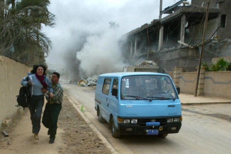 Greek journalist Efetefia Pentaraki and her Iraqi guide Maohamad al-Rashid run for cover as the al-Salehiya telecomunication center is hit by a missile during a coalition air raid on Baghdad 30 March 2003. The raid took place as journalists were on a tour organized by the information ministry to be shown damage caused by overnight bombing. One man was injured and another was treated for shock.      AFP PHOTO/Patrick BAZ (Photo by PATRICK BAZ / AFP)