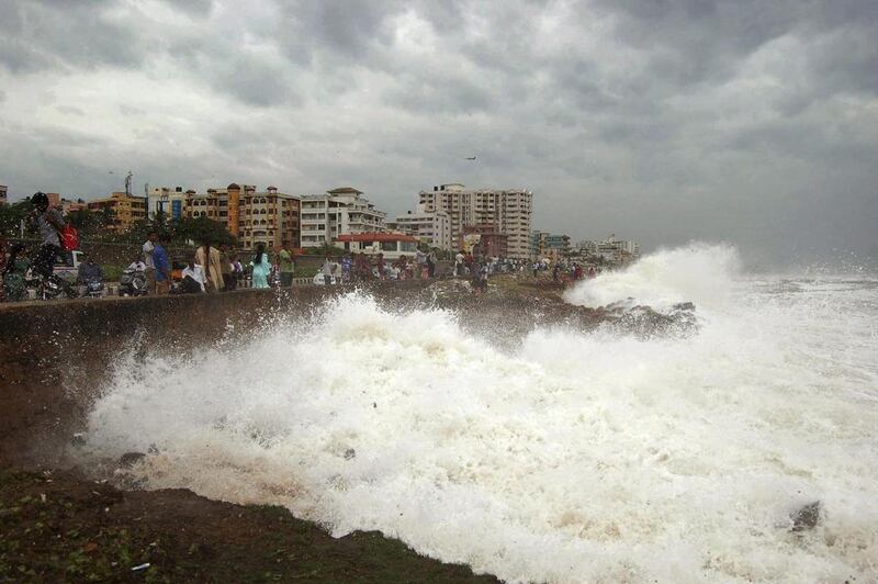 Indian people watch high tide waves as they stand at the Bay of Bengal coast in Vishakhapatnam, India,. AP Photo