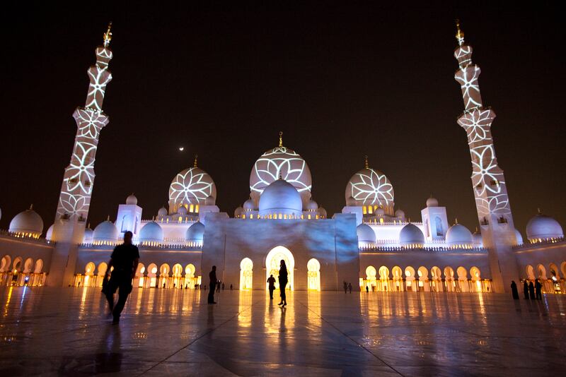 People enjoy a light show projected on the walls of the Sheikh Zayed Mosque on Tuesday evening, Nov. 29, 2011, in celebration of the upcoming 40th anniversary of the UAE creation at the mosque in Abu Dhabi. (Silvia Razgova/The National)
