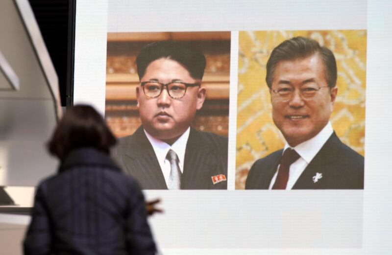 A woman walks past a public TV screen showing a news clip with the photos of North Korean leader Kim Jong Un, left, and South Korean President Moon Jae-in, in Tokyo, Wednesday, March 7, 2018. After years of refusal, Kim is willing to discuss the fate of his atomic arsenal with the United States and has expressed a readiness to suspend nuclear and missile tests during such talks, a senior South Korean official said Tuesday.  Kim also agreed to meet with South Korea's president next month. (AP Photo/Eugene Hoshiko)