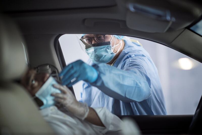 epa08358816 A nurse uses a swab to test the passenger of a car at a Covid19 drive-through testing centre in Dubai, United Arab Emirates, 12 April 2020. The United Arab Emirates set up 13 new drive-through Covid-19 testing centers capable of carrying an average of 500 tests per day in each center. The Ministry of Health in UAE said 648,195 tests of covid-19 coronavirus were conducted till 11 April 2020.  EPA/MAHMOUD KHALED  ATTENTION: This Image is part of a PHOTO SET