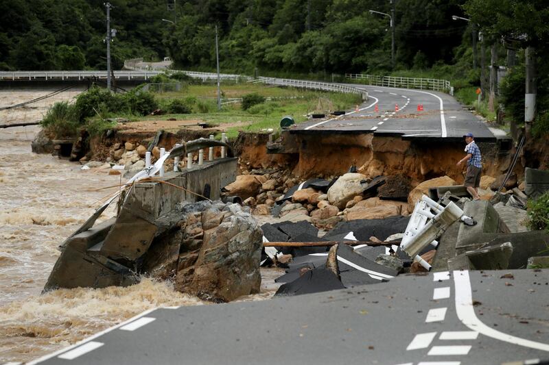 A resident struggles to cross a collapsed road destroyed by heavy rain in Higashihiroshima, Hiroshima Prefecture, Japan. EPA