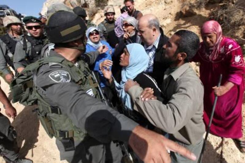 epa03002302 A Palestinian woman addresses an Israeli soldier a they remove protesters gathered to portest against the construction of a section of Israel's controversial separation barrier in the West Bank village of Walajeh, near the biblical West Bank town of Bethlehem on 13 November 2011.  EPA/ABED AL HASHLAMOUN *** Local Caption ***  03002302.jpg