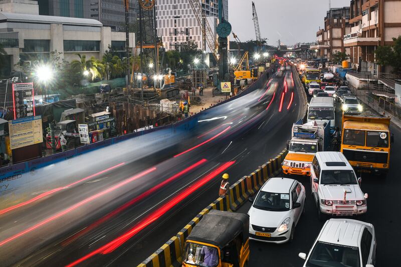 A labourer waits to cross a busy intersection at rush hour in Chennai, India. EPA