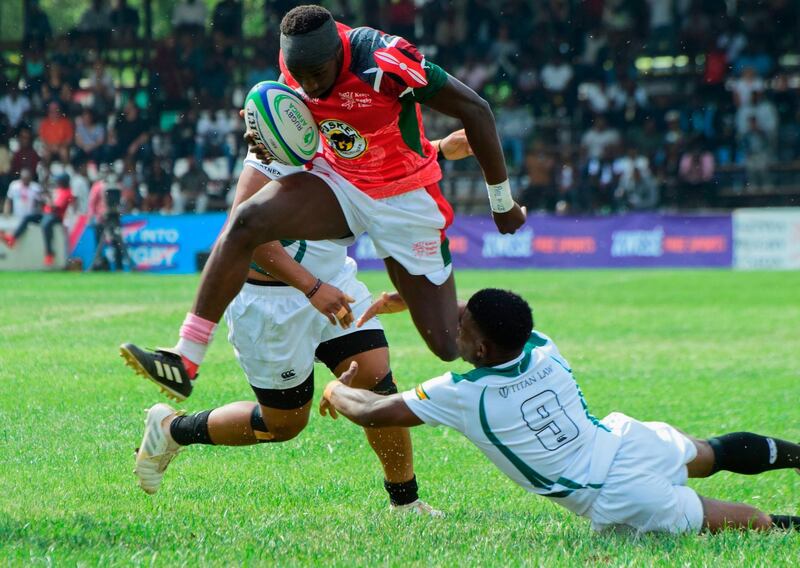 TOPSHOT - Kenya's fly-half Isaac Adimo (C) vies with Zimbabwe's Lenience Tamwera (R) during the 2018 Rugby African Gold Cup match between Kenya and Zimbabwe in Nairobi on June 30, 2018, which acts a qualifier for the 2019 Rugby World Cup in Japan. Kenya won the match 45-36. / AFP / KEVIN MIDIGO

