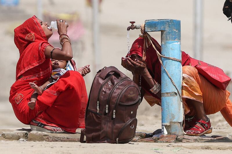 Women drink tap water on a hot summer afternoon during a heatwave in Prayagraj, India. AFP