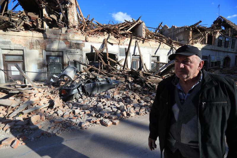 A man stands on a street next to destroyed houses on a street after an earthquake in Petrinja, Croatia.  REUTERS