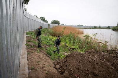 Policemen patrol alongside a steel wall at the Evros river, near the village of Poros, at the Greek-Turkish border. AP Photo