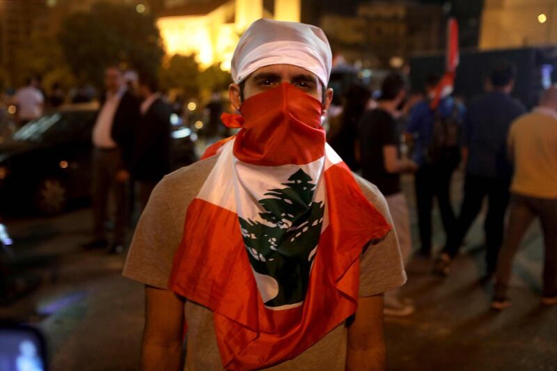 A Lebanese anti-government protester masked with his country's flag block a main avenue in reaction to the speech of Lebanon's president Michel Aoun in Beirut. AFP