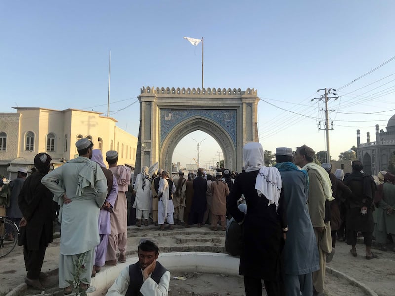 Taliban militants raise their flag as they gather a day after taking control of key southern city Kandahar.