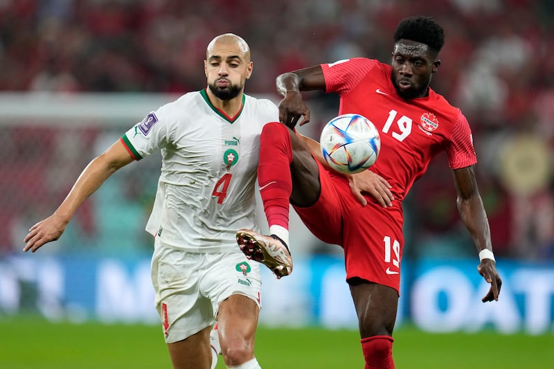 Morocco's Sofyan Amrabat, left, and Alphonso Davies of Canada battle for possession. Goals from Hakim Ziyech and Youssef En-Nesyri ensured the North Africans finished top of Group F. AP