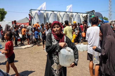 A woman walks with a water container after filling up with others from a truck loaded with water cisterns in Rafah in the southern Gaza Strip on June 25. AFP