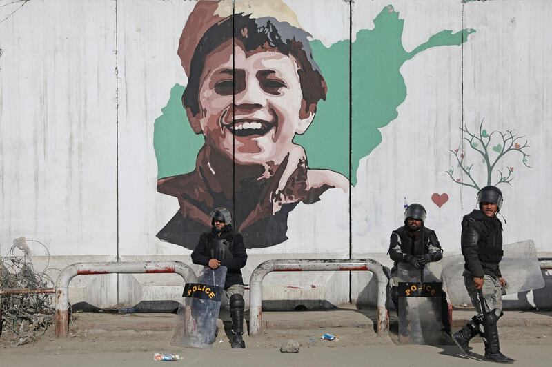 Afghan policemen in riot gear sit in front of a mural during a protest demonstration by supporters of Afghanistan's leading presidential candidate, Abdullah Abdullah, in Kabul, Afghanistan. AP Photo