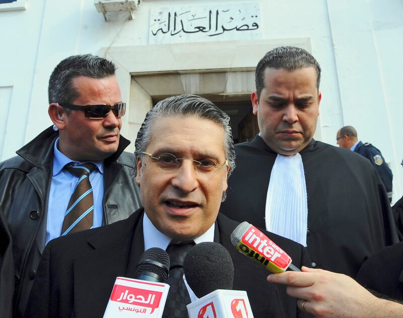 FILE - In this Jan.23 2012 file photo, the owner of the Tunisian private channel Nessma TV, Nabil Karoui, center, leaves the Tunis courthouse after attending his trial. A leading presidential candidate in Tunisia, Nabil Karoui, co-owner of a private TV station, has been arrested and jailed in a case involving alleged tax evasion and money laundering. (AP Photo/Hassene Dridi, File)