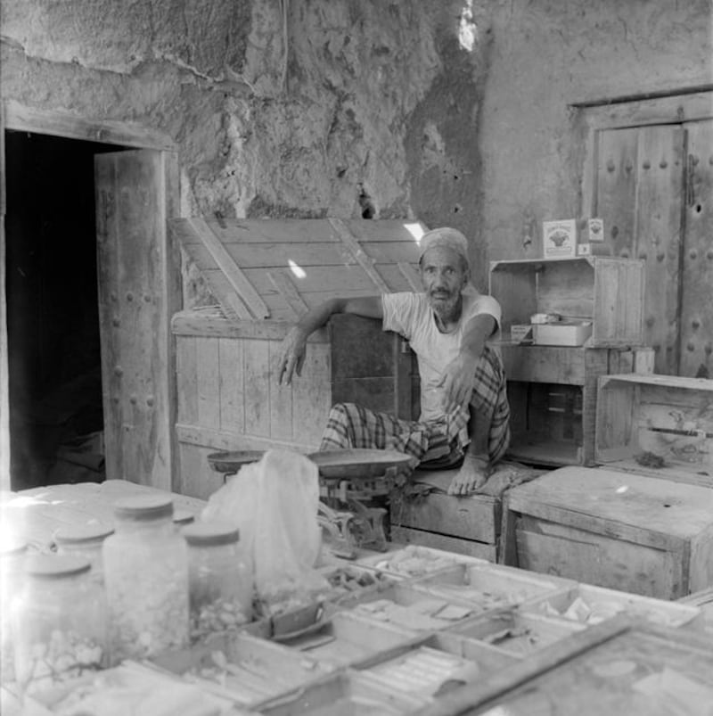 Archival photograph of the Trucial States shot by photographer Guy Gravett in 1962. A trader in the Abu Dhabi Souq. The Flower Basket matches visable on the right are still sold here. 

Eds note** Karen *** Permission needed before use. Contact Crispin Gravett Cpgravett@aol.com. $150 one print use and 5 years online. 