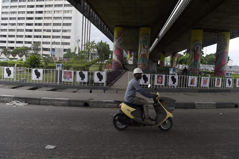 A man drives his scooter past portraits of some of the 200 Chibok schoolgirls abducted by Boko Haram Jihadists five years ago at Falomo roundabout in Lagos, on April 13, 2019.  Civil societies and rights activists  have line up activities across the country to mark the April 14, 2014 abduction of 276 schoolgirls from the Government Girls Secondary School at the remote town of Chibok in Borno State, northeastern Nigeria, which brought global attention to the conflict that has left more than 27,000 people dead since the Boko Haram conflict began in 2009. / AFP / PIUS UTOMI EKPEI
