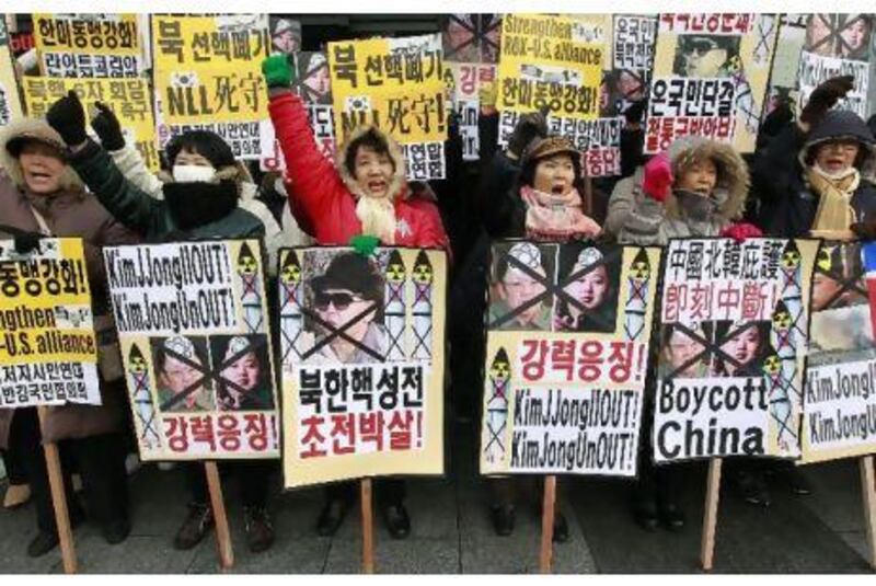 Protesters holding portraits of North Korean leader Kim Jong-il and his son Kim Jong-un shout slogans during an anti-North Korea rally near the US Embassy in Seoul yesterday.