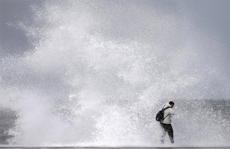 A walker gets soaked by a wave in Barcelona as a low pressure hits the coast in northeastern Spain. EPA