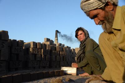 This photograph taken on March 28, 2018 shows Afghan female labourer Sitara Wafadar, 18, who dresses as a male in order to support her family, working at a brick factory next to her elderly father (R) in Sultanpur village in Surkh Rod district, in Afghanistan's eastern Nangarhar province.
Sitara Wafadar yearns for long hair like other girls. Instead, the Afghan teenager has disguised herself as a boy for more than a decade, forced by her parents to be the "son" they never had. / AFP PHOTO / Noorullah SHIRZADA / TO GO WITH Afghanistan-children-gender, FEATURE by Noorullah Shirzada