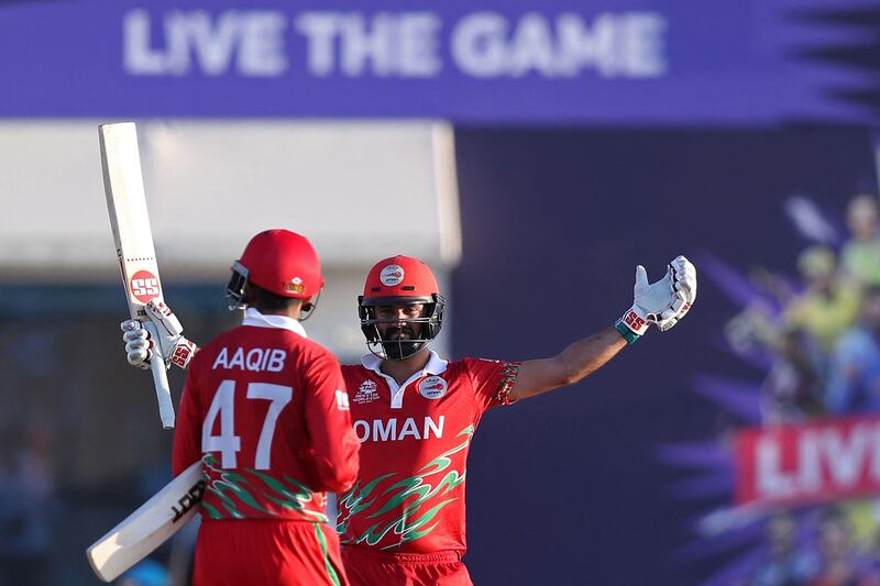 Oman's Jatinder Singh, right, and Aqib Ilyas celebrate their 10-wicket win over Papua New Guinea at the T20 World Cup first round match at the Oman Cricket Academy Ground in Muscat on Sunday, October 17, 2021. AFP